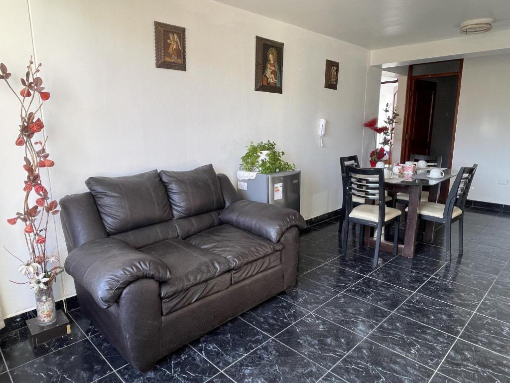 ein Wohnzimmer mit einem braunen Ledersofa und einem Tisch in der Unterkunft Departamento Amoblado en el Centro de Cusco in Cusco