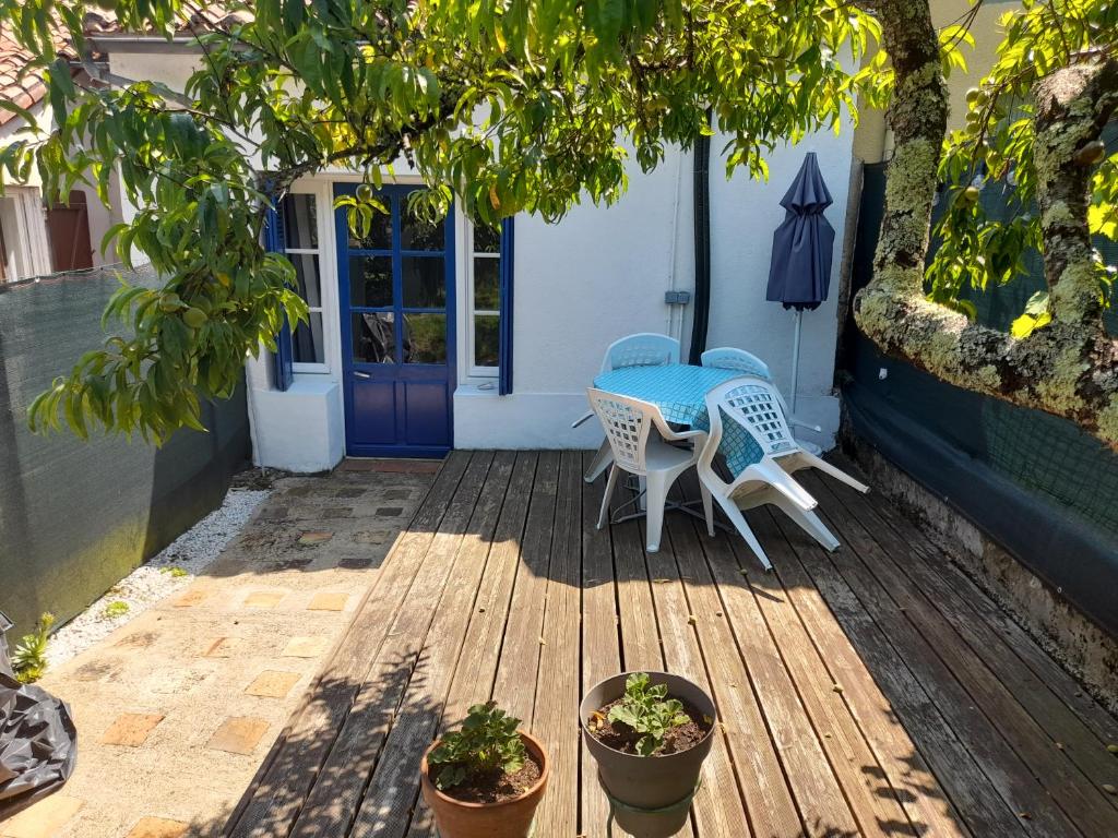 a patio with a table and chairs on a deck at Beau Maison in Le Vigeant