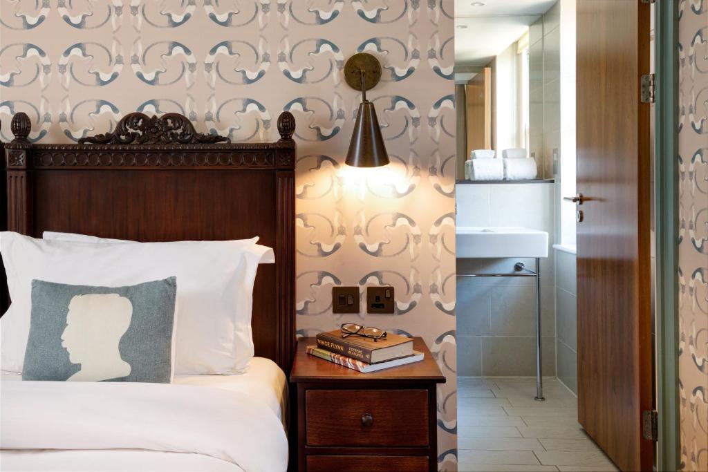 um quarto com uma cama e uma mesa lateral com livros em Morton Hotel em Londres