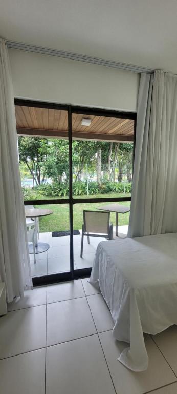 a bedroom with a bed and a patio with a table at ILOA Residence Flat Alagoas in Barra de São Miguel
