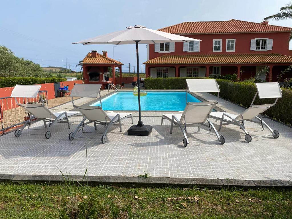 a group of chairs and an umbrella next to a pool at A Casa do Comandante in Lagoa