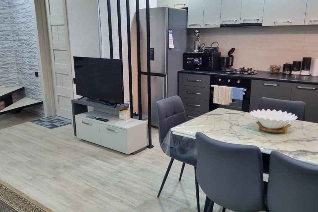 a kitchen with a table with chairs and a television at My House in Borjomi