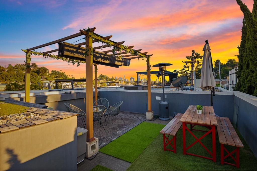 a rooftop patio with a table and a umbrella at Chic, Modern Silver Lake Oasis with Rooftop Panoramic DTLA Views & Private Garage in Los Angeles