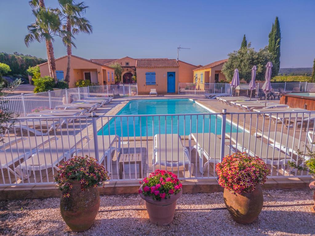 a swimming pool with potted plants in front of it at Le Mas des Sagnes in Collias