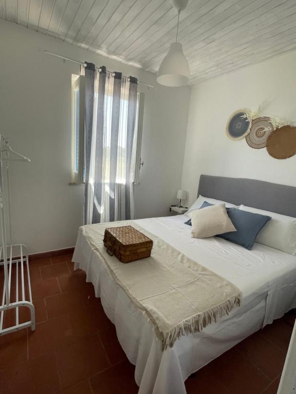 a white bedroom with a bed with a basket on it at Villa Paso in Ustica