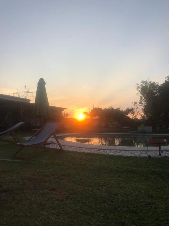 a sunset over a pool with a table and chairs at Quinta das Caçadoras - Animal lovers only in Palmela