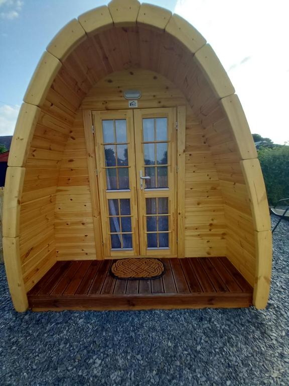 uma grande cabana de madeira com uma janela no meio em Pen y Buarth Pod - Caravan Site em Caernarfon