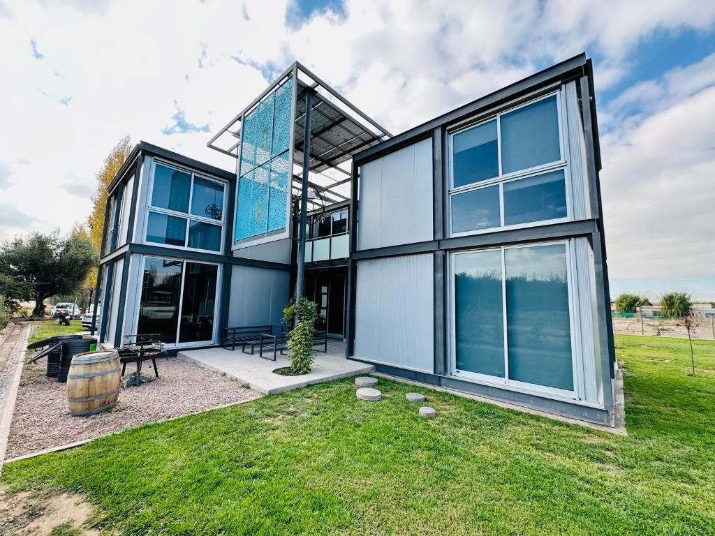 una casa con grandes ventanas de cristal en el césped en Cubos de Chacras AZUL en Mendoza