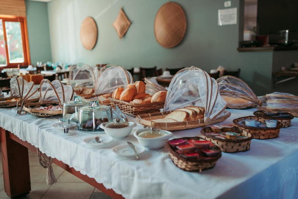 a table with baskets of bread and other foods on it at Pousada Brigitte in Barra do Sahy