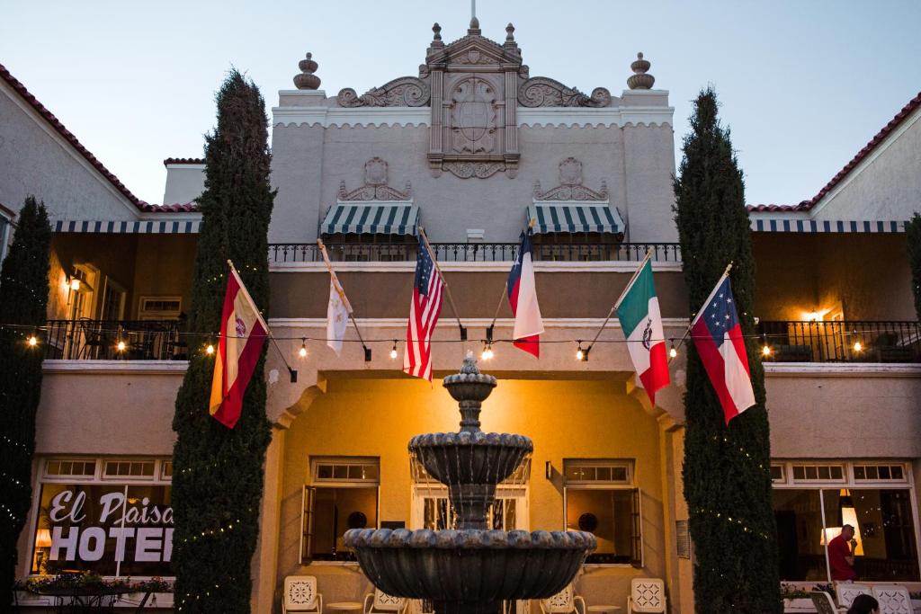 un hôtel avec une fontaine en face d'un bâtiment arborant des drapeaux dans l'établissement The Hotel Paisano, à Marfa