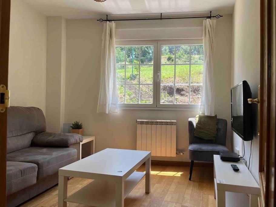 a living room with a couch and a table and a window at Apartamento junto al parque in Ponferrada