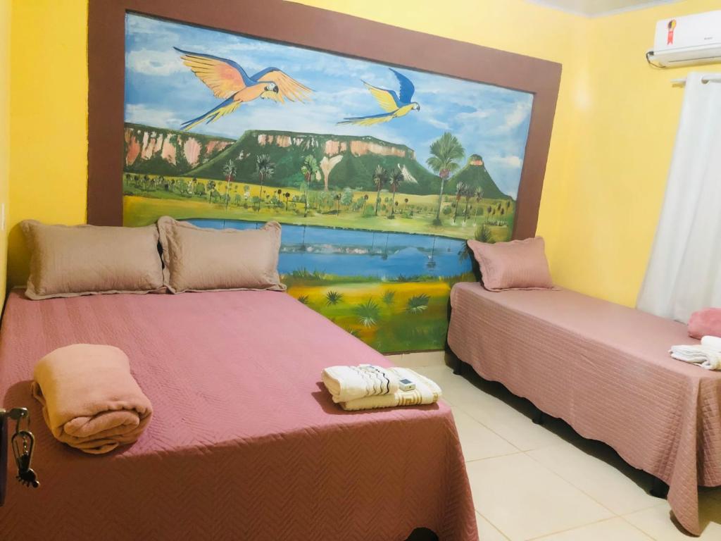 2 camas en una habitación con un cuadro en la pared en Pousada Voadores Jalapão en Mateiros