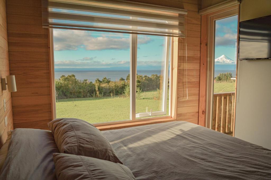a bedroom with a bed and a large window at Ave Lodge Frutillar in Frutillar