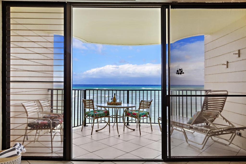 a balcony with a table and chairs and the ocean at Kahana Reef 318 in Kahana