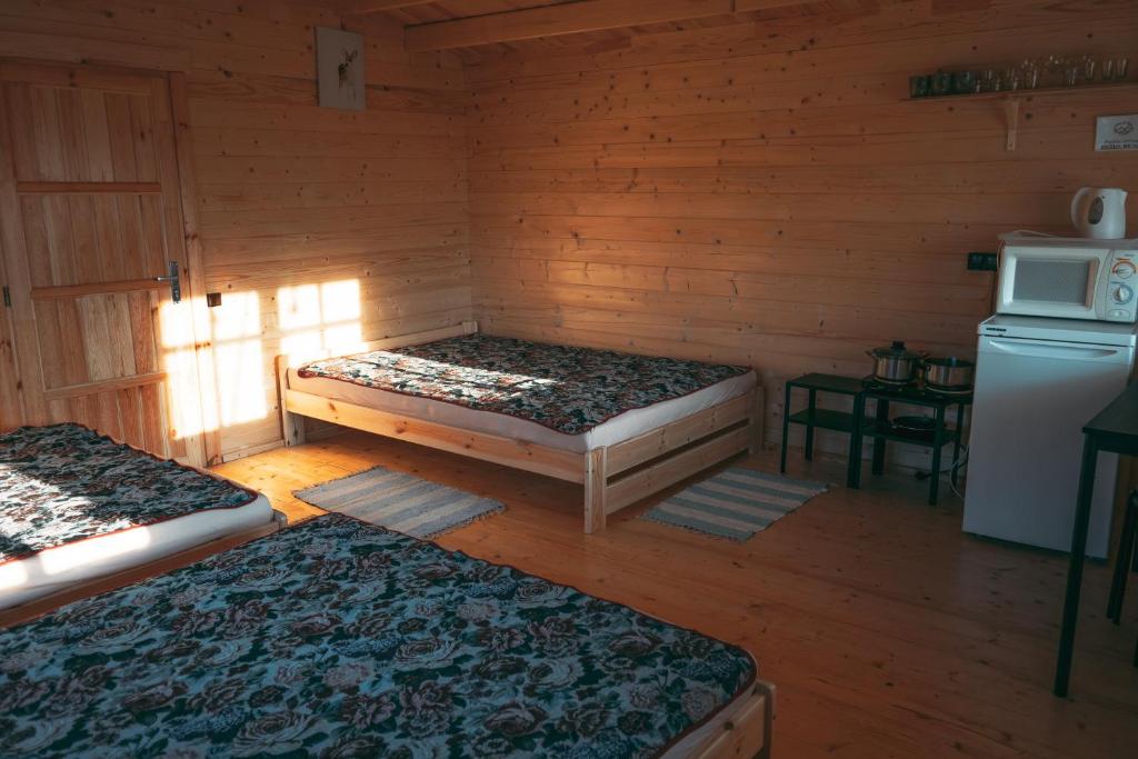 um quarto com duas camas num chalé de madeira em Šeimos Namelis Adomo Sodyboje prie ežero 35 km nuo Vilniaus šalia Dubingių 