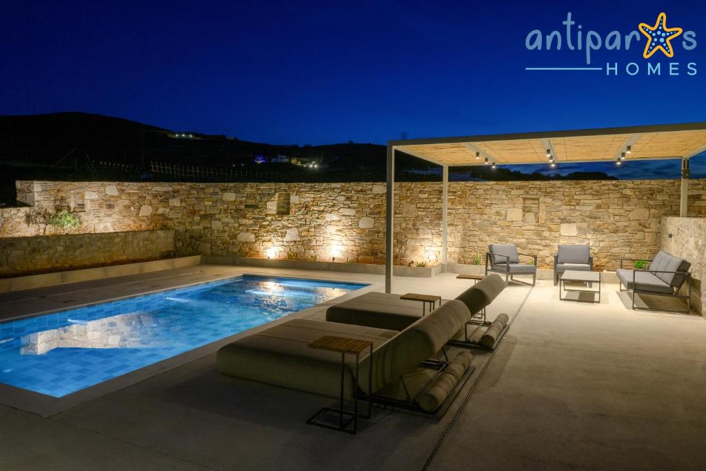 a swimming pool with chairs and a table and a building at Antiparos Homes in Antiparos