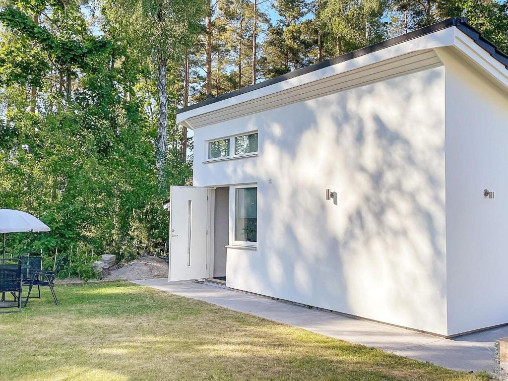 a white garage with a table and an umbrella at Holiday home Sölvesborg XII in Sölvesborg