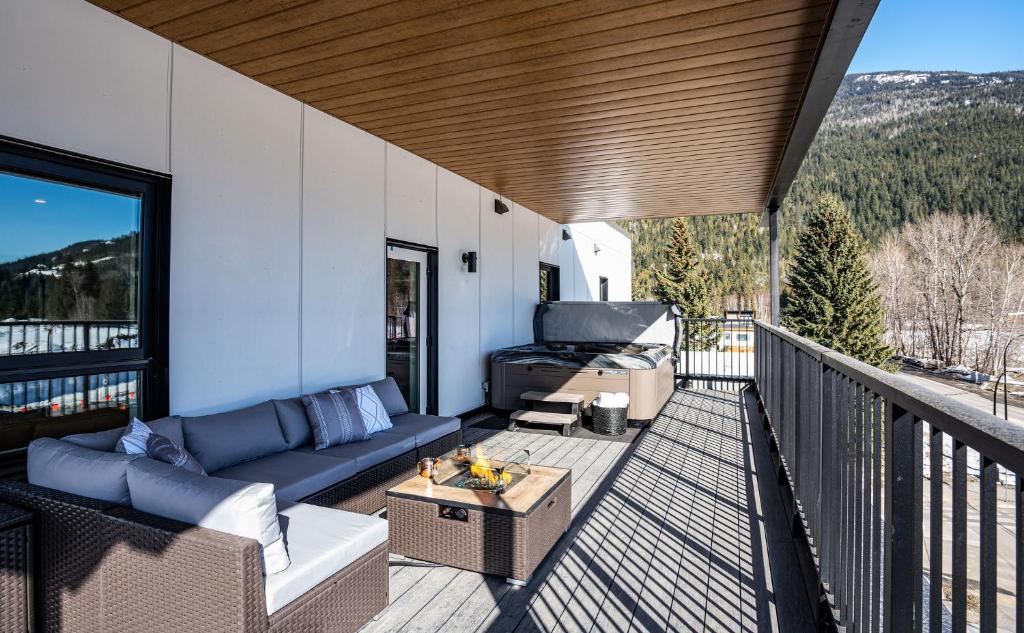 a patio with a couch and a table on a balcony at The Big Deck by Revelstoke Vacations in Revelstoke