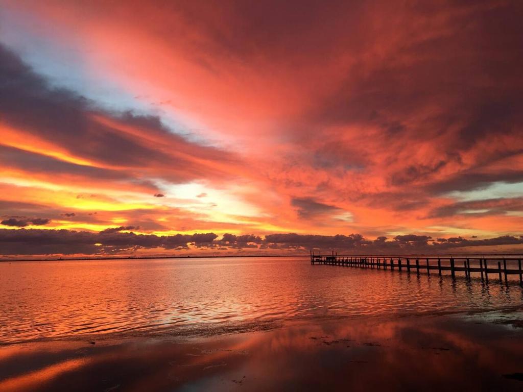 a sunset over the ocean with a pier at Waterfront Laguna Madre Bayhouse - Fishing, Birding & Family Retreat in Flour Bluff