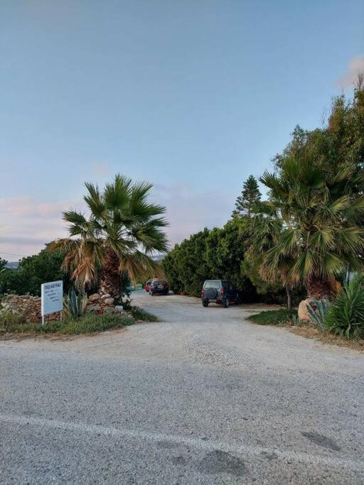 a road with palm trees and a car parked on it at Peaceful and quiet apartment. in Aliki