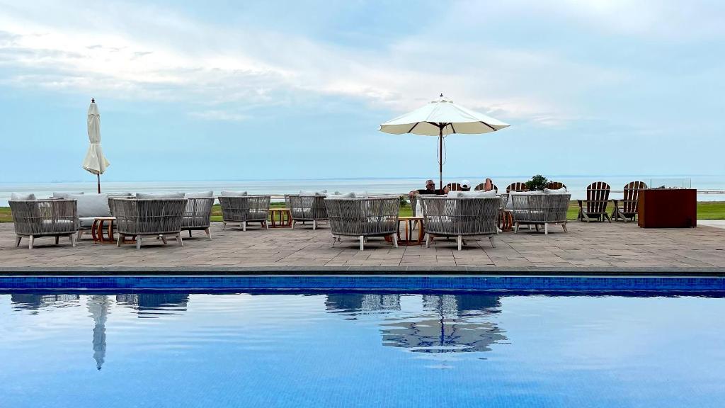 uma mesa e cadeiras e um guarda-sol ao lado de uma piscina em Barsebäck Resort Hotell em Löddeköpinge