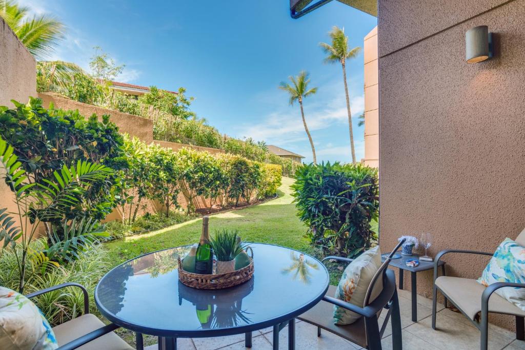 a patio with a table and chairs and palm trees at Kahana Villa E111 in Kahana