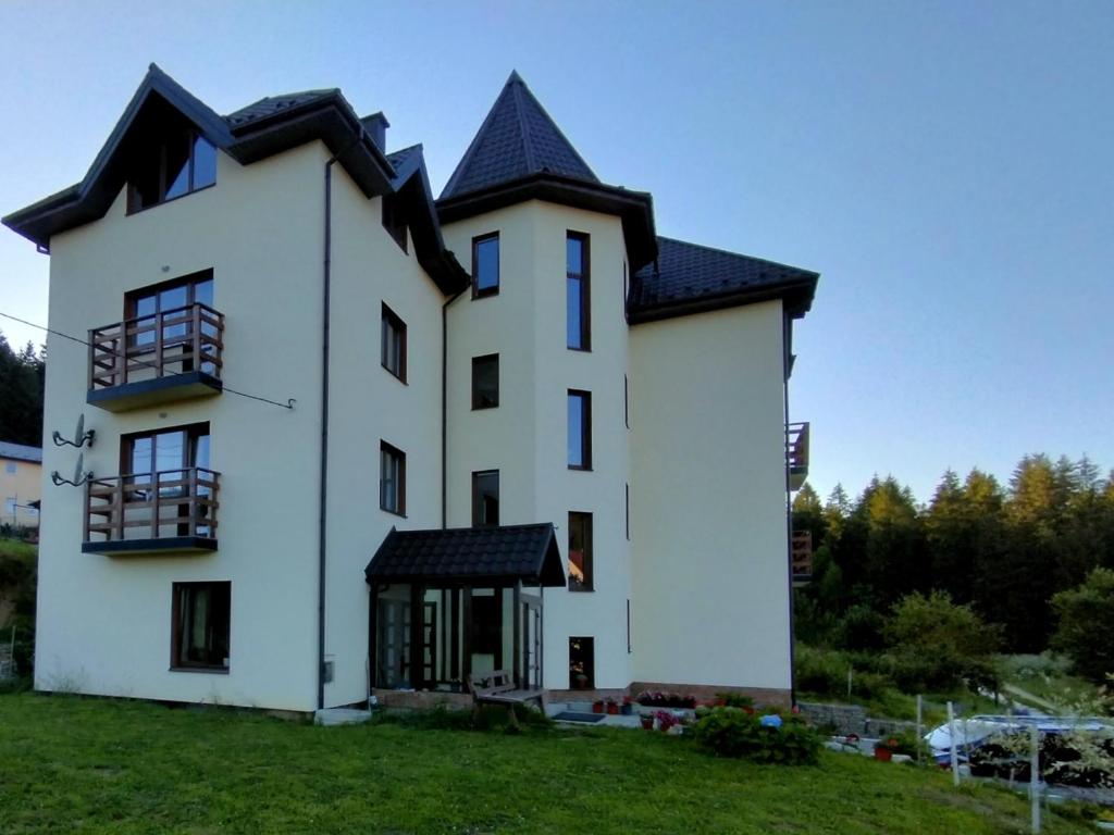 a white house with a black roof at Рудий Лис in Skhidnitsa