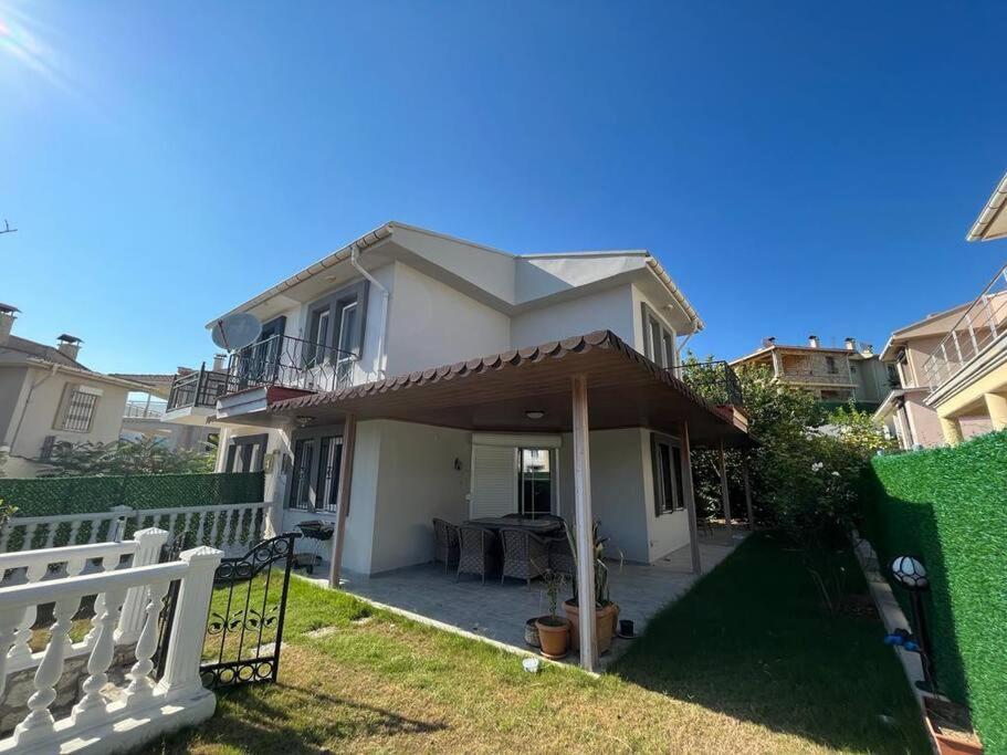 una casa con una valla blanca y un patio en Alaçatıda bahçeli müstakil ev, en Alacati