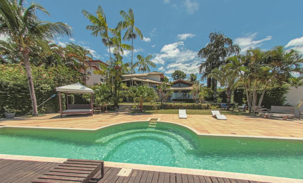 una piscina con terraza de madera y una casa en Casa de Férias Casa Mia, en Santa Cruz Cabrália