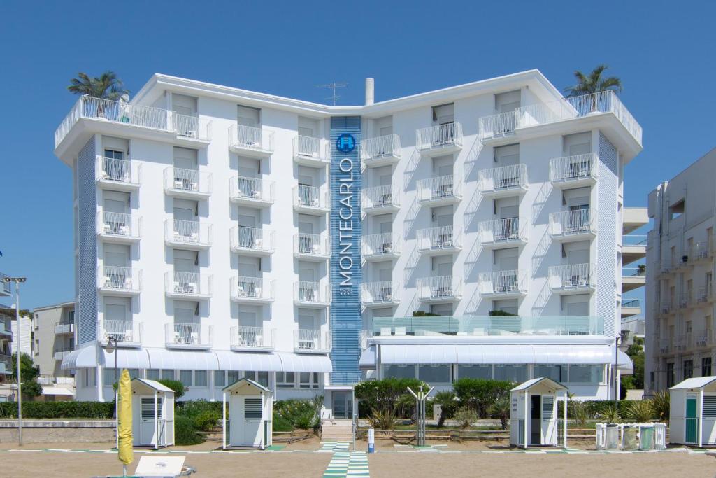 un edificio bianco con un cartello blu davanti di Hotel Montecarlo a Caorle