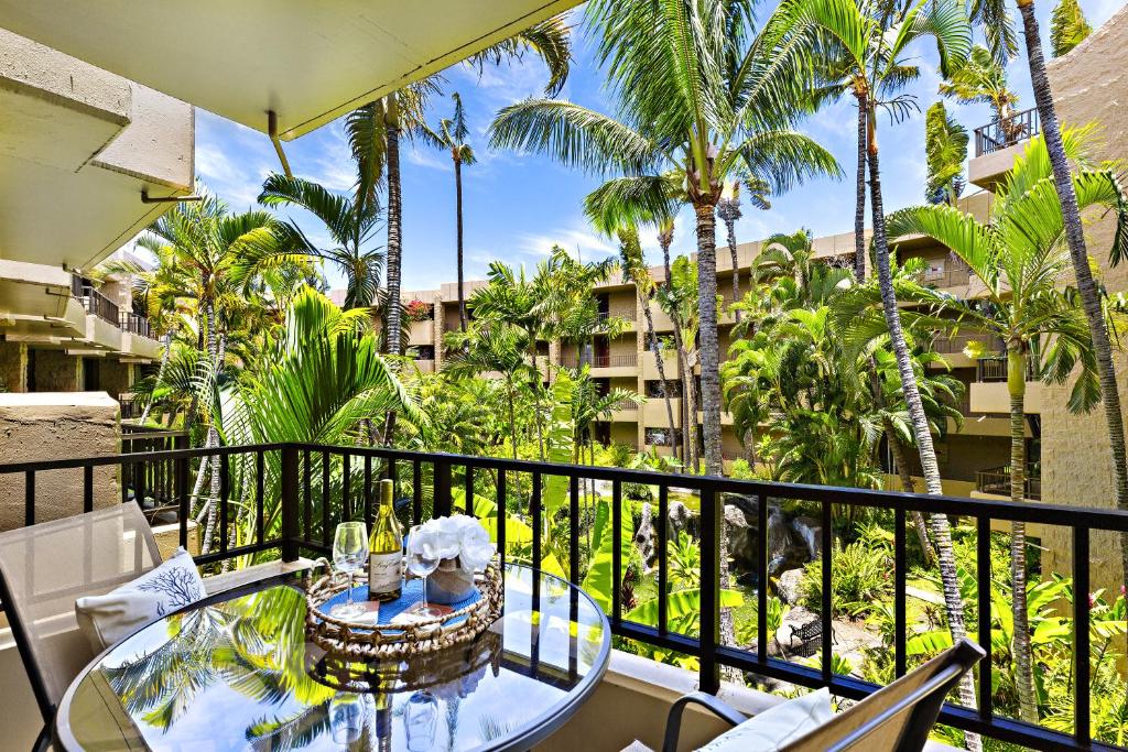 a balcony with a table and chairs and palm trees at Paki Maui 319 in Honokowai