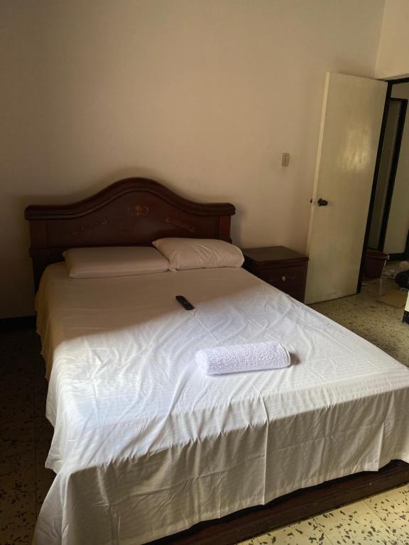 Una cama con sábanas blancas y un libro. en CASA FAMILIAR AMPLIA MUY FRESCA en Medellín