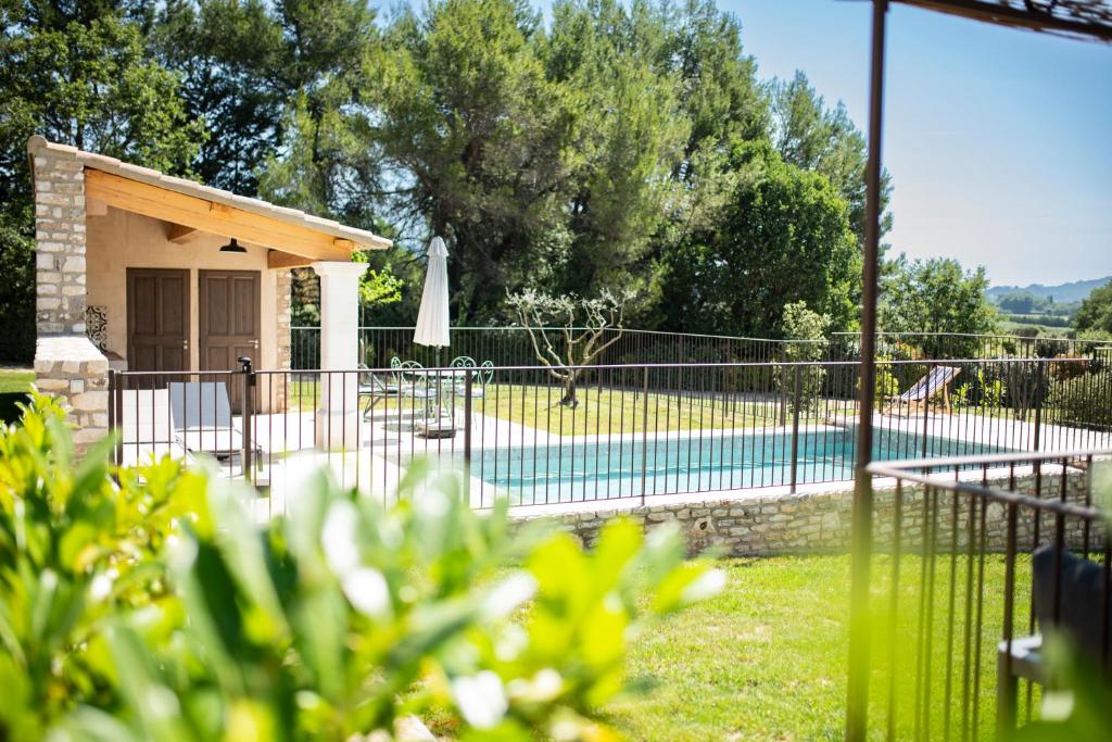 a house with a fence and a swimming pool at Bastide Toujours Dimanche, Maison de vacances avec vue & piscine privée in Gordes