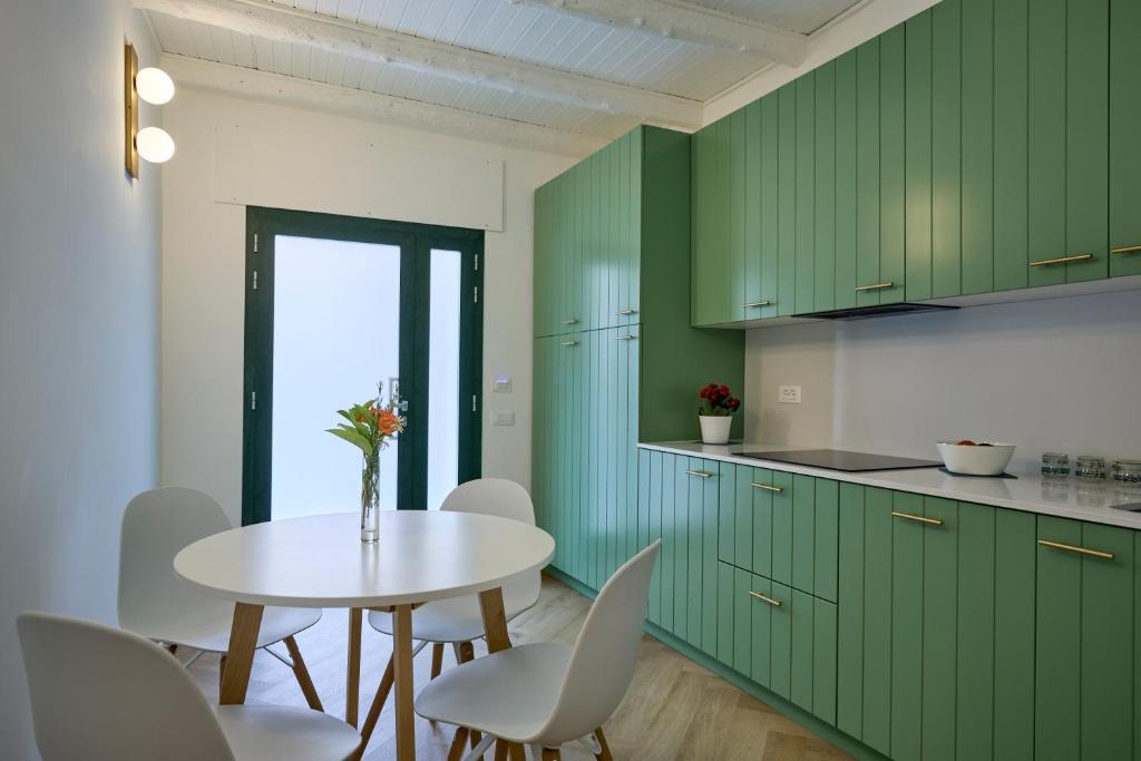a kitchen with green cabinets and a table and chairs at CAMERANOAPARTMENTS - L'Angolo della Piazza in Camerano