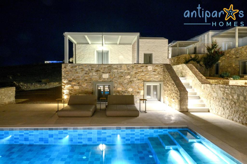 a swimming pool in front of a villa at night at Antiparos Homes in Antiparos