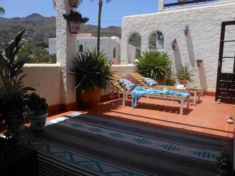 eine Terrasse mit einer Bank und Topfpflanzen auf einem Haus in der Unterkunft Las Palmeras del Cantal in Mojácar