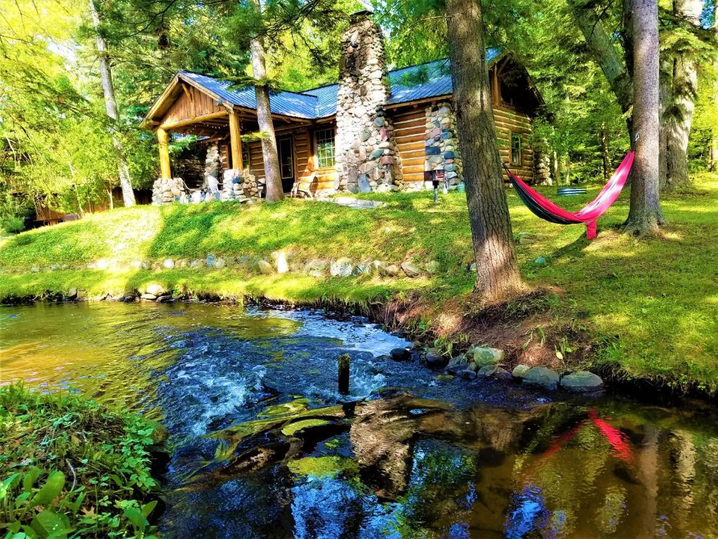 a log cabin with a hammock next to a river at Steps to Beach-Hot Tub-Fireplace-Northern Original in Traverse City