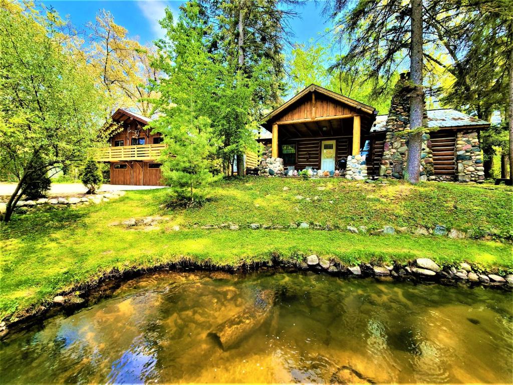 una baita di tronchi con un laghetto di fronte ad essa di Exclusive 2 Chalet Stay-HotTub-Fireplace-Beachside a Traverse City