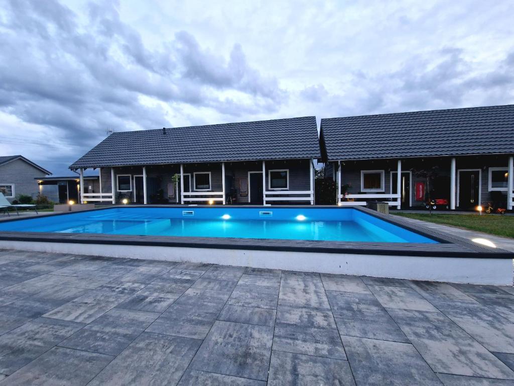a swimming pool in front of a house at U Ani Domki z podgrzewanym basenem in Rewal