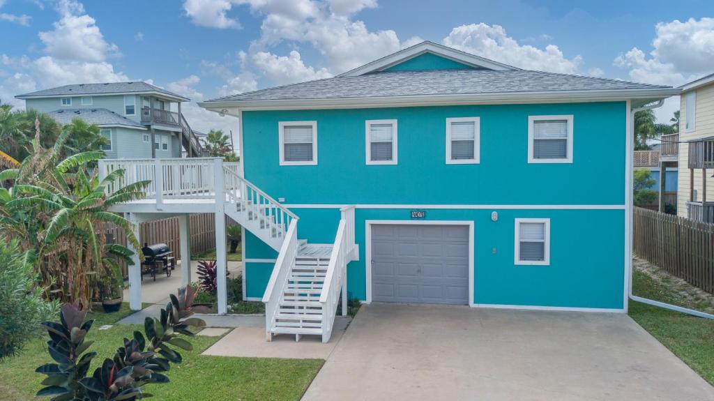 a blue house with a garage at Blue Horizon HUGE Private Pool and yard with Outside shower! in Port Aransas