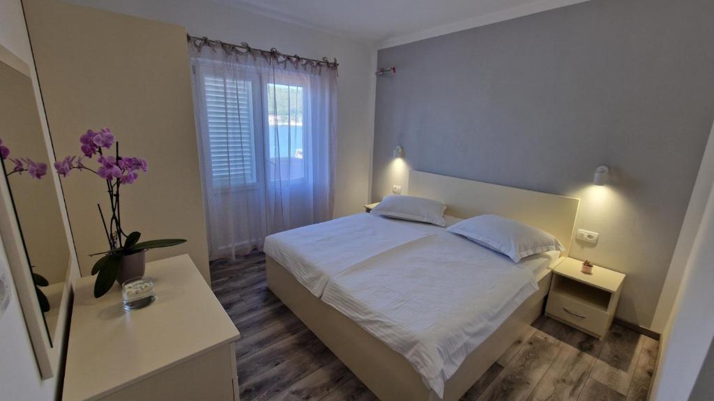 a white bedroom with a bed and a window at Miljenko&Miljenka in Supetarska Draga
