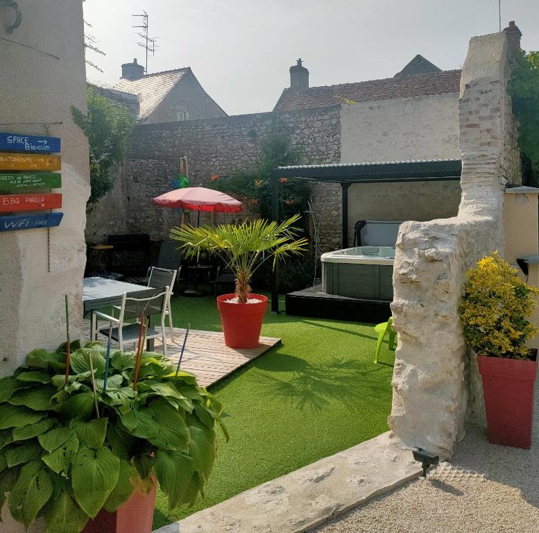 une terrasse avec de l'herbe, des plantes, une table et un parasol dans l'établissement home ferman, à Saint-Dyé-sur-Loire