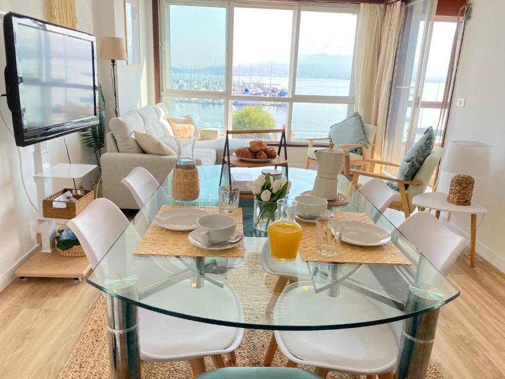 una sala de estar con una mesa y sillas de cristal en Precioso piso en Baiona con vistas al mar, en Baiona