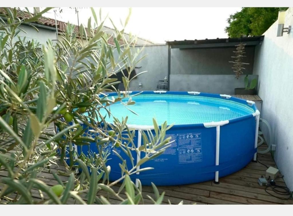 un jacuzzi bleu posé sur une terrasse à côté d'un bâtiment dans l'établissement Chez Gaël et Julie villa 5 mins plages pisc, clim, à Sérignan