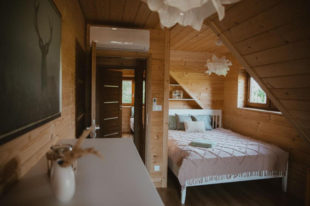 1 dormitorio con 1 cama en una cabaña de madera en House Polesie, en Urszulin