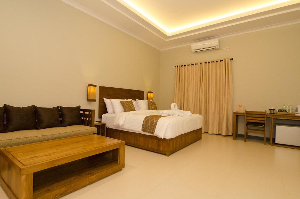 una camera da letto con un letto, un divano e un tavolo di Syailendra Hotel Syariah a Jepara