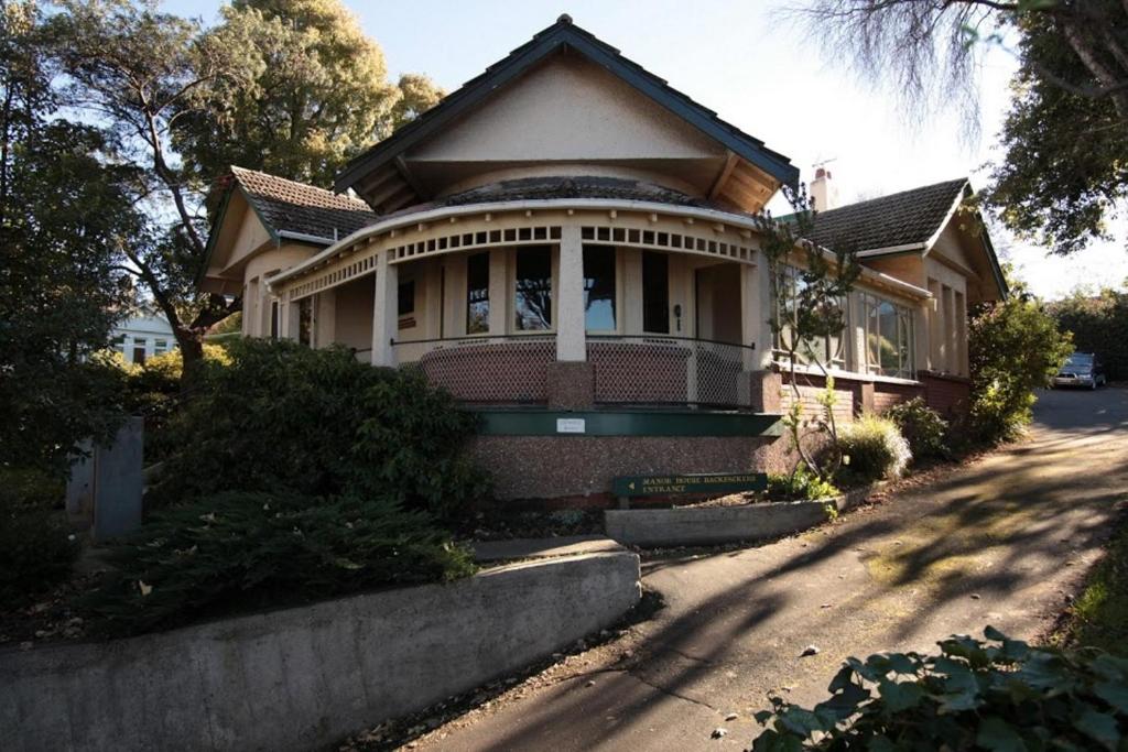 uma casa ao lado de uma rua em Manor house backpackers em Dunedin