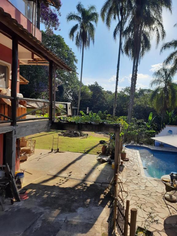 un patio trasero con piscina y palmeras en Chácara piscina aquecida en Cotia