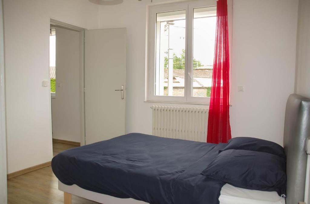 - une chambre avec un lit et une fenêtre avec des rideaux rouges dans l'établissement Appartement Lisa, à Lézignan-Corbières