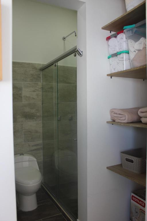 La salle de bains est pourvue de toilettes et d'une douche en verre. dans l'établissement Coveñas Hermoso Apartamento familiar en caribe campestre, à Coveñas